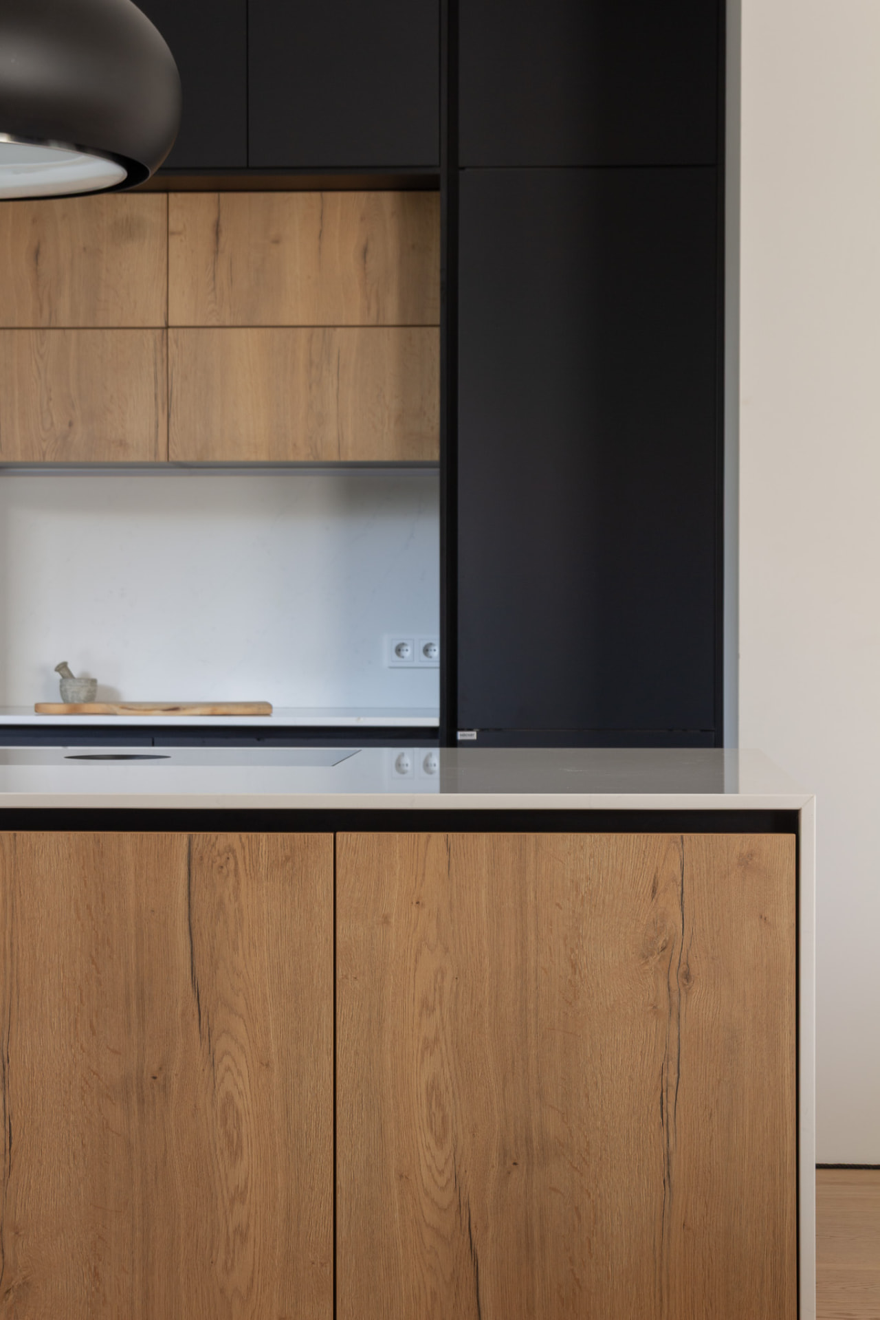 Close view of the kitchen with black cabinetry, oak fronts and the island worktop