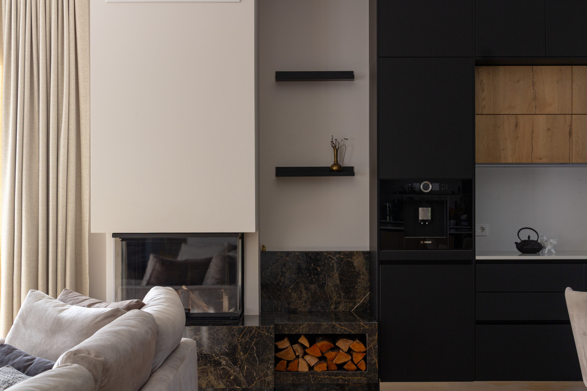 Marble fireplace beside dark built-in kitchen cabinetry