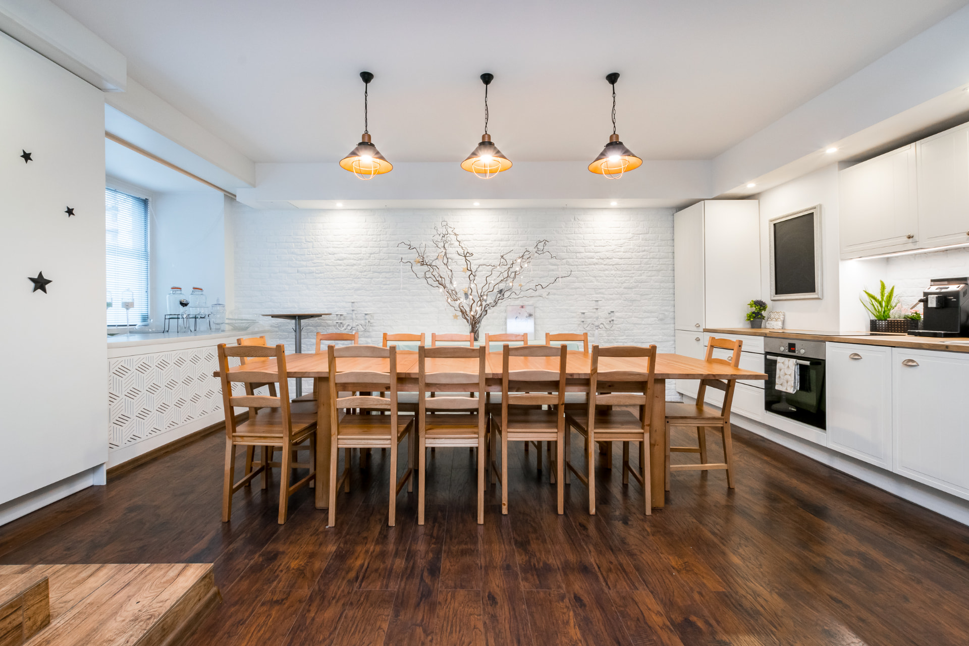 Flexible event studio arranged around a long timber table with kitchen and brick wall beyond