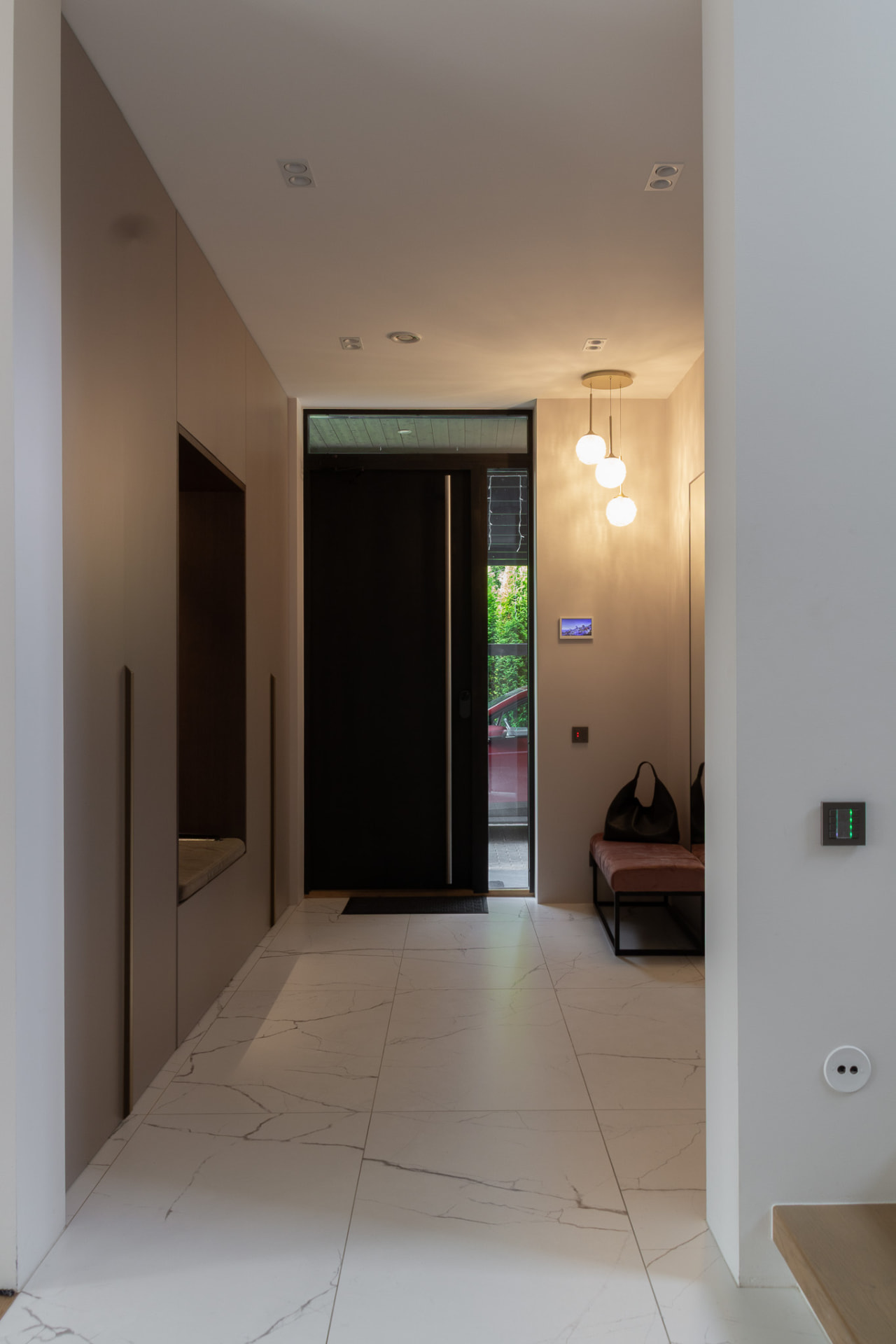 Entrance hall looking towards the dark front door, with glass pendants and marble floor