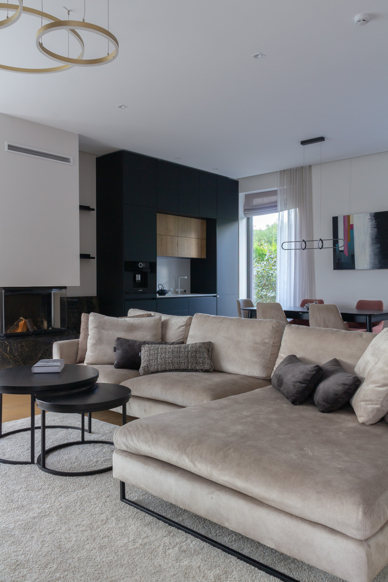 Pale sectional sofa with the dark kitchen and dining area behind it