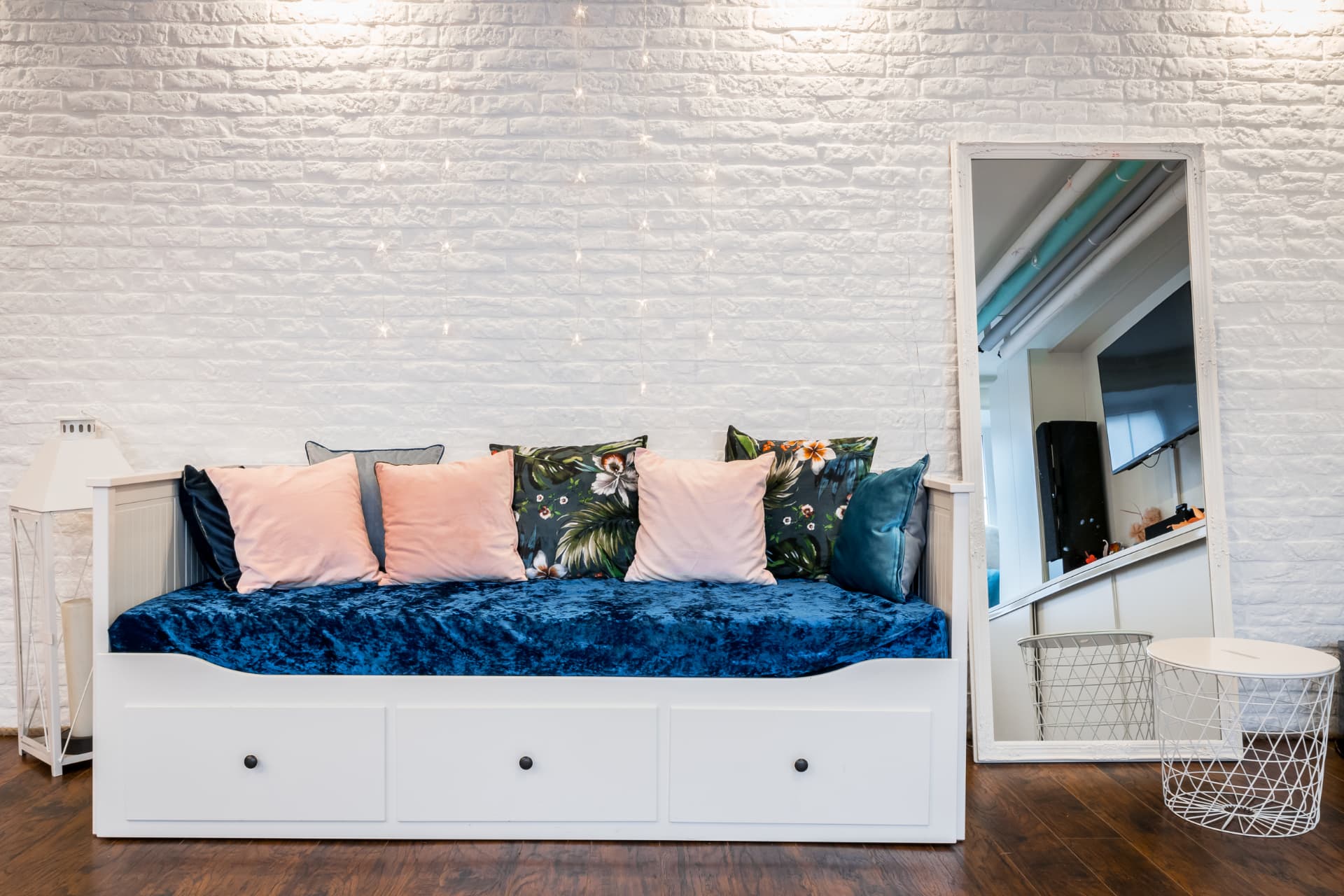 Built-in daybed with blue and blush textiles against the white brick feature wall
