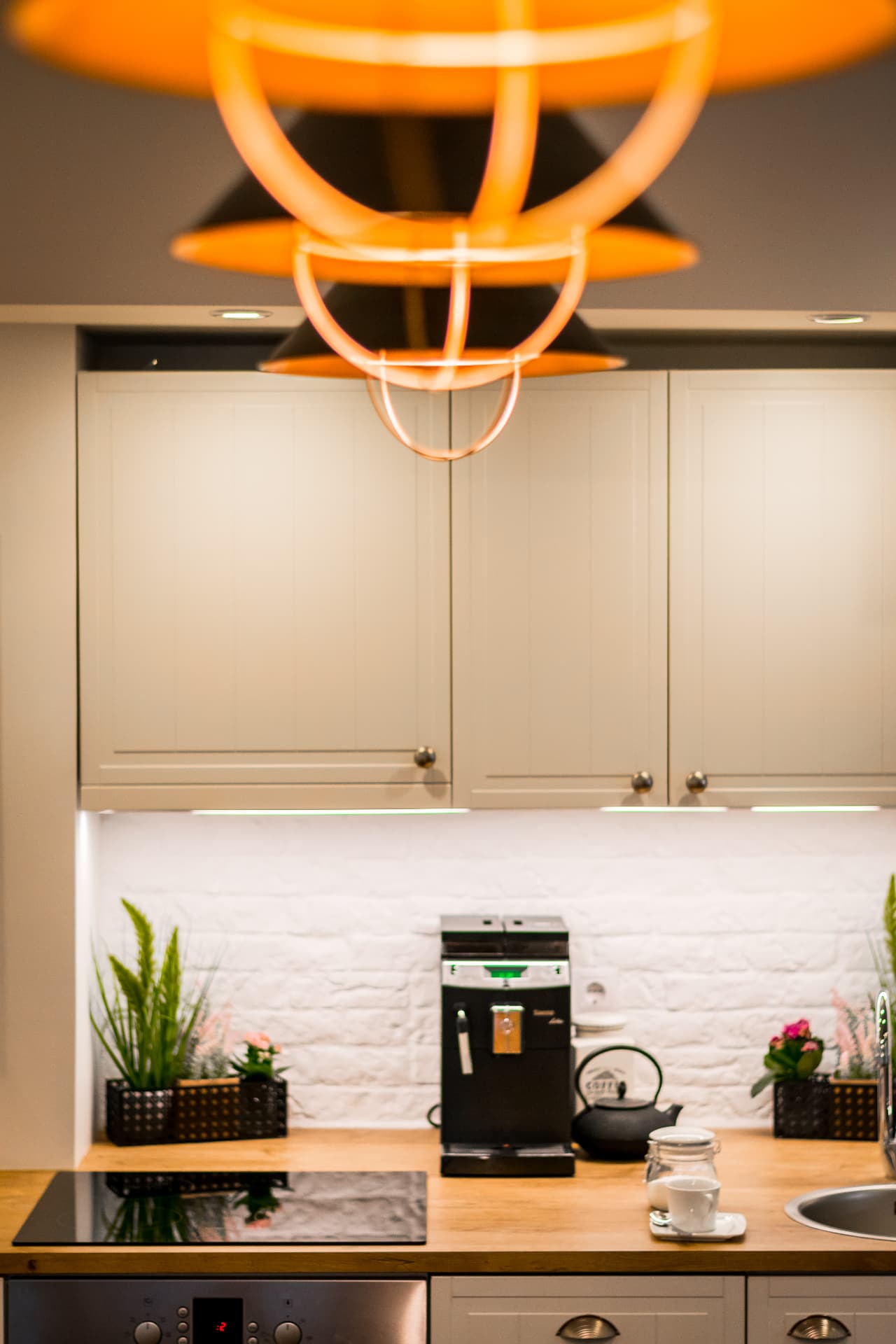 Vertical detail of orange pendant lights above the event studio kitchen