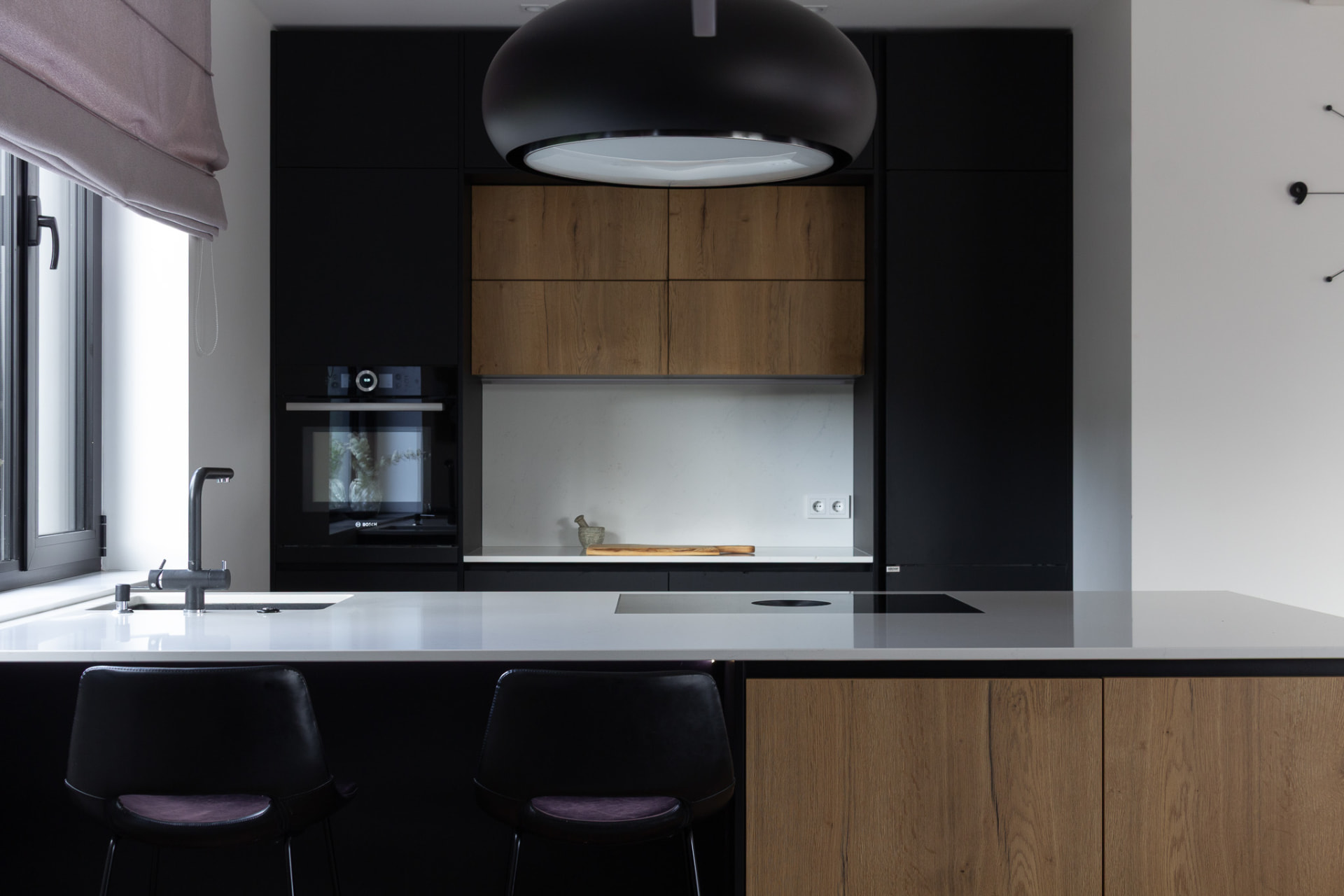 Frontal kitchen view with a light island and large black pendant